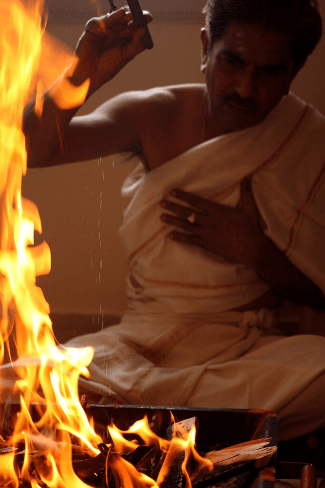 A Hindu priest performing a homa (fire sacrifice) in the orthodox Tantric tradition. Such fire rituals in Dakshinachara Tantra use clarified butter and herbs as offerings to Divine Fire (Agni), aligning with Vedic purity and serving as a meditative, purifying practice.