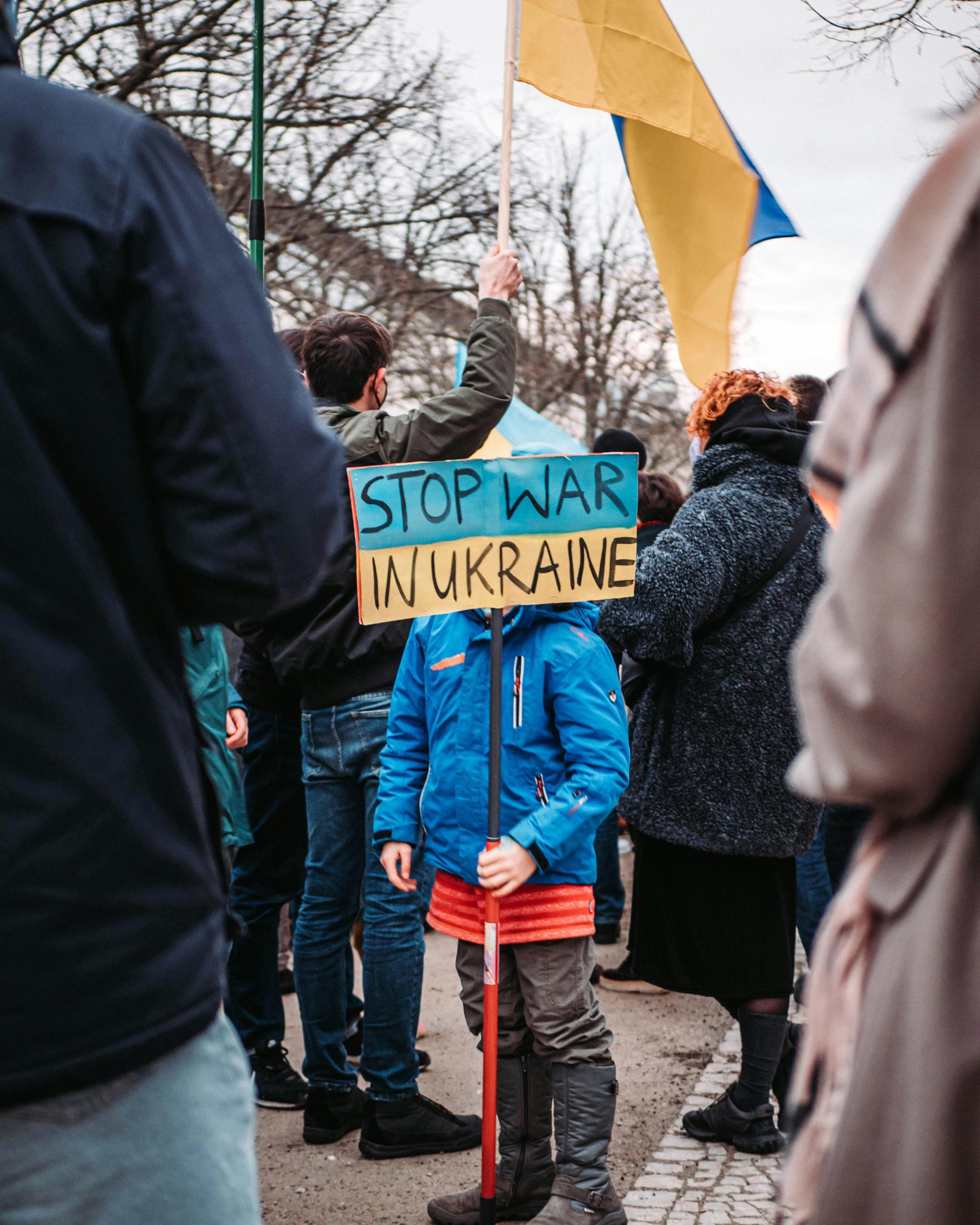 A child holds a 'Stop War in Ukraine' sign during a peaceful protest outdoors in Berlin, Germany.