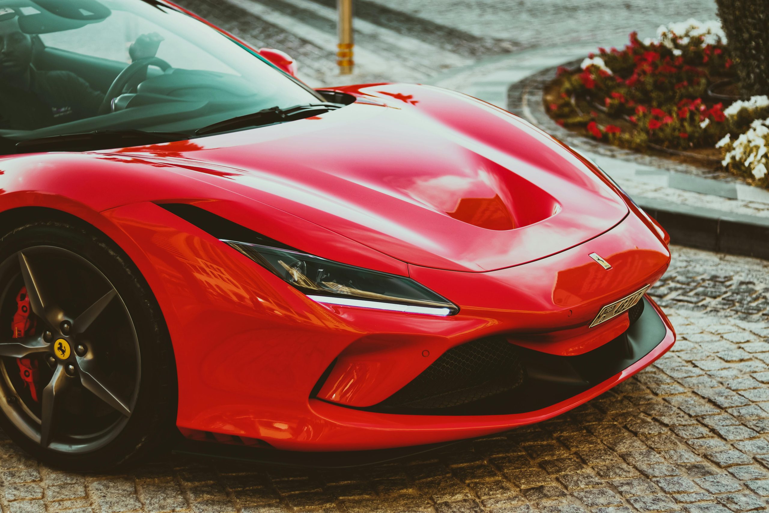 Stunning red Ferrari sports car parked on a cobblestone path in Dubai, showcasing luxury and elegance.