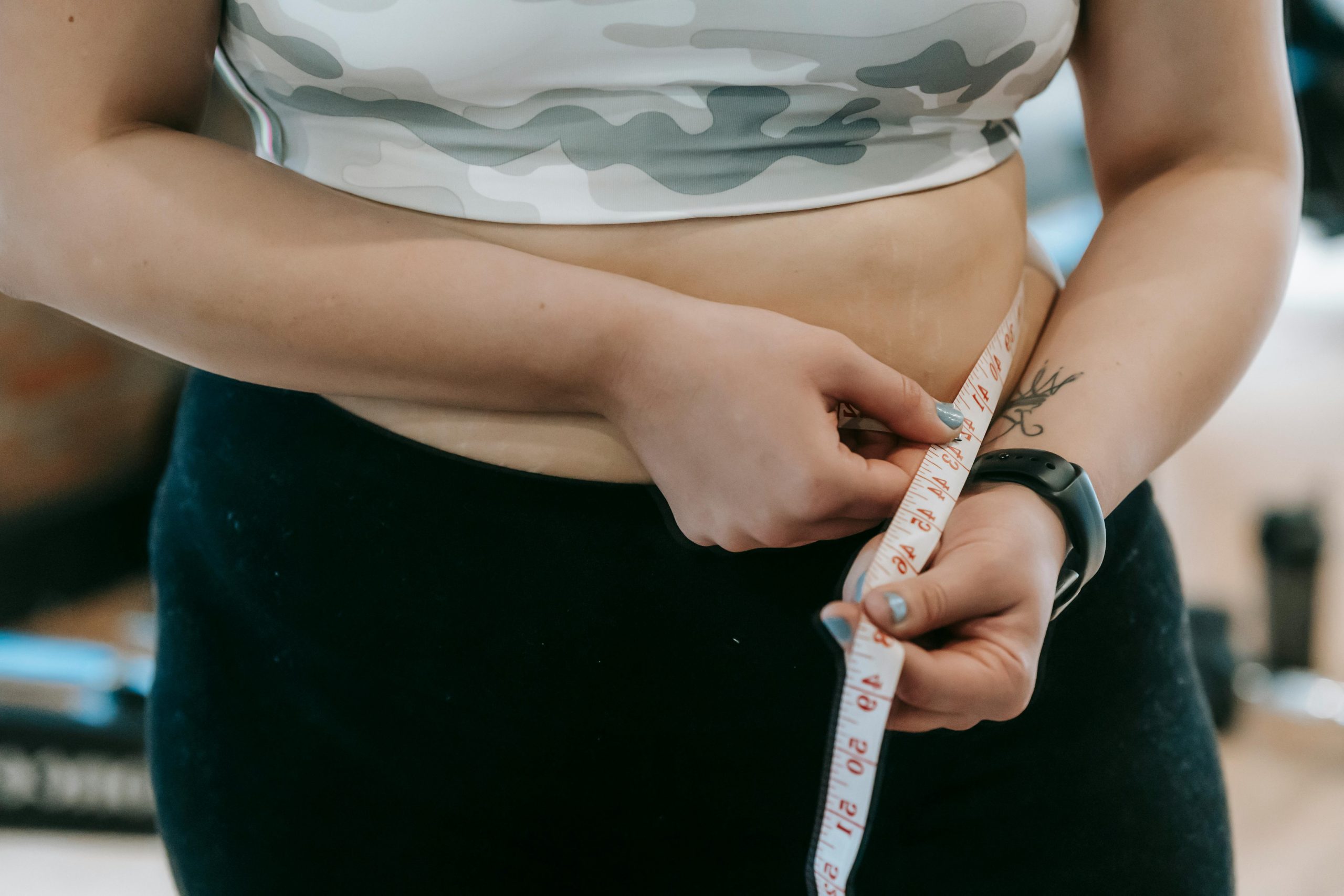 Close-up of a woman's waist being measured with a tape. Fitness and health concept.